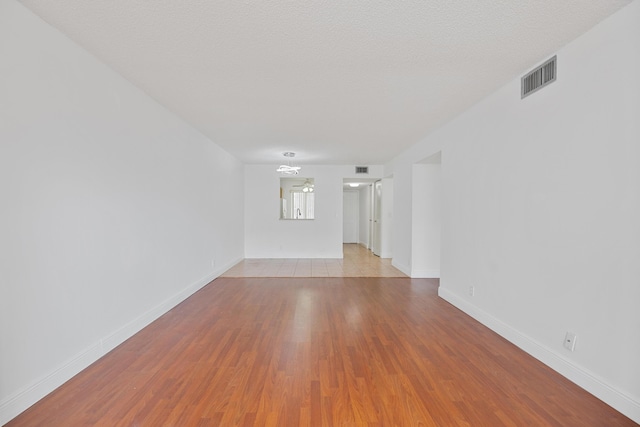 spare room featuring a textured ceiling and light hardwood / wood-style flooring