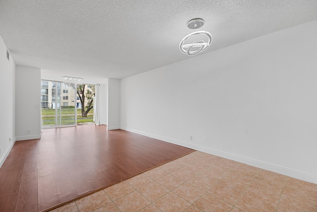 spare room featuring a textured ceiling, expansive windows, light tile patterned floors, and a notable chandelier