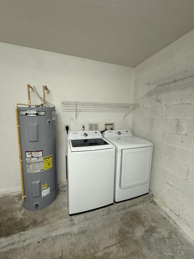 laundry room featuring electric water heater, washer and clothes dryer, and a textured ceiling