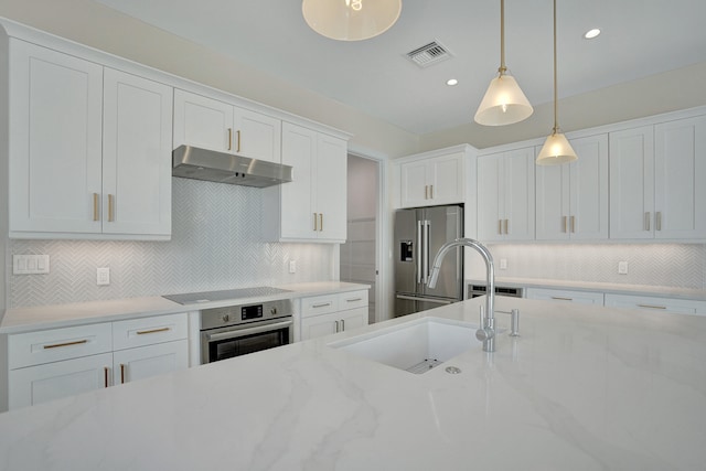 kitchen with white cabinets, stainless steel appliances, sink, backsplash, and hanging light fixtures