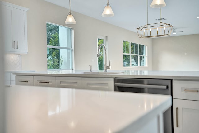 kitchen featuring dishwasher, decorative light fixtures, white cabinetry, tasteful backsplash, and sink