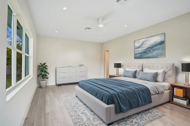 bedroom featuring ceiling fan, light hardwood / wood-style floors, and multiple windows