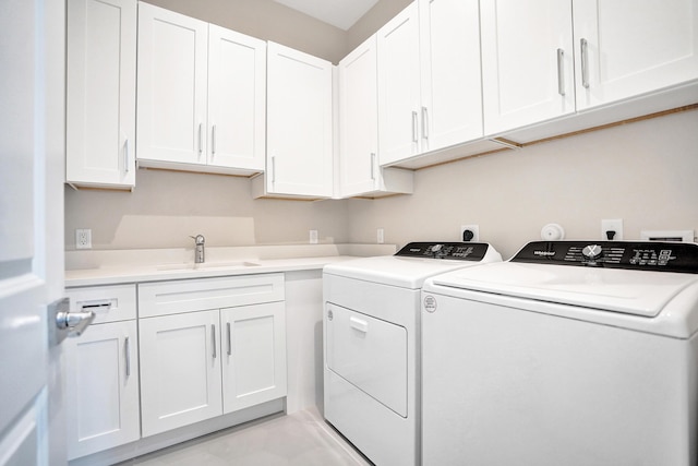 clothes washing area with washer and dryer, sink, and cabinets