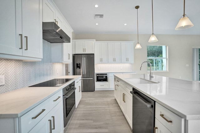 kitchen with a center island with sink, pendant lighting, sink, stainless steel appliances, and white cabinets