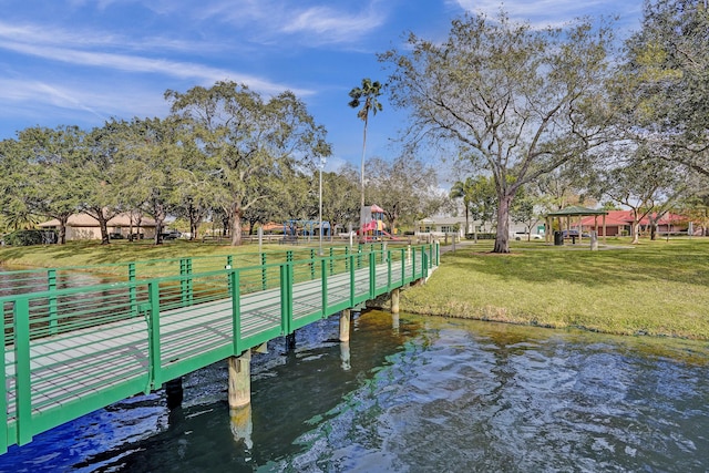 dock area with a playground, a yard, and a water view