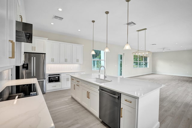 kitchen featuring white cabinetry, stainless steel appliances, hanging light fixtures, light stone countertops, and sink