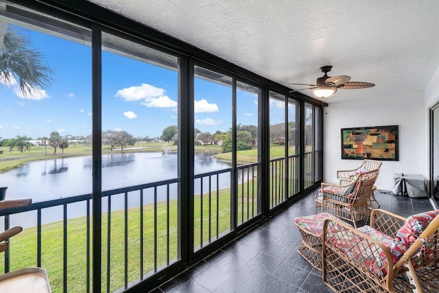 sunroom with ceiling fan and a water view