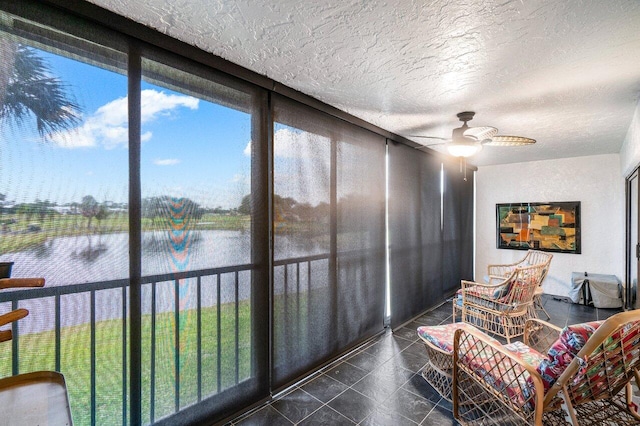 sunroom featuring a water view and ceiling fan