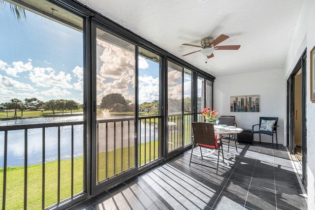 sunroom / solarium featuring ceiling fan and a water view