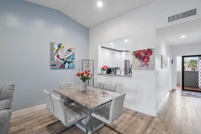 dining space with light hardwood / wood-style floors and lofted ceiling