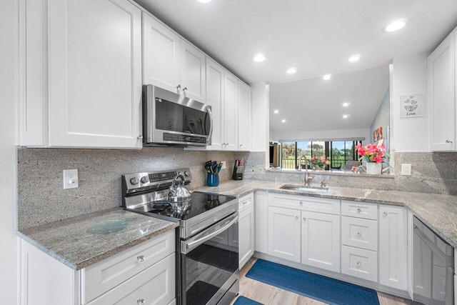 kitchen with stainless steel appliances, lofted ceiling, white cabinetry, and sink