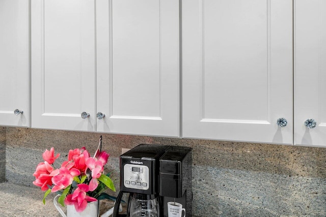 interior details with backsplash, stone countertops, and white cabinets