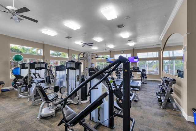 workout area with a healthy amount of sunlight, a textured ceiling, ceiling fan, and ornamental molding