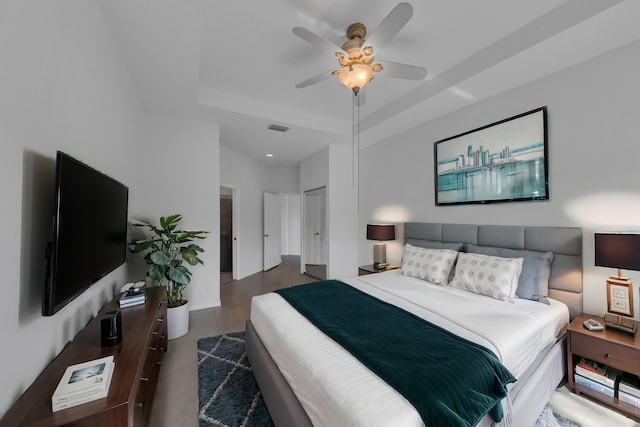 bedroom with a raised ceiling, ceiling fan, a closet, and dark hardwood / wood-style floors