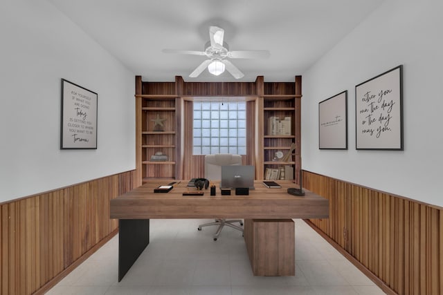 office space featuring ceiling fan, wood walls, and built in features