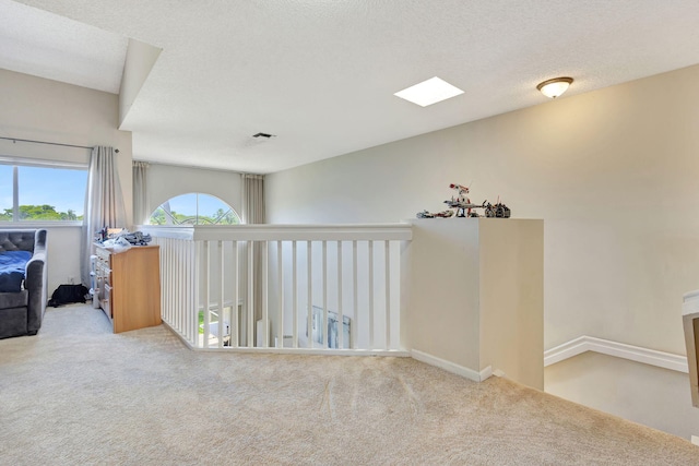 corridor featuring carpet, a textured ceiling, and a skylight