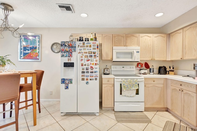 kitchen featuring light brown cabinets, light tile patterned flooring, and white appliances