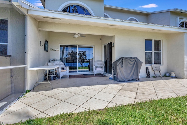 view of exterior entry with ceiling fan and a patio area