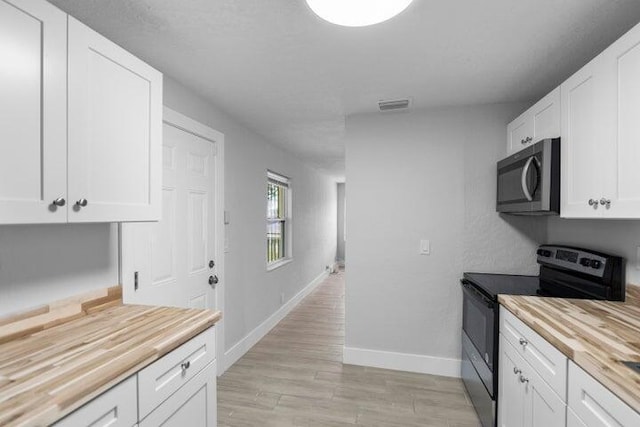 kitchen with stainless steel range with electric stovetop, light hardwood / wood-style floors, white cabinets, and wooden counters