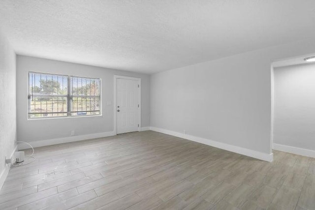 unfurnished room with light hardwood / wood-style flooring and a textured ceiling