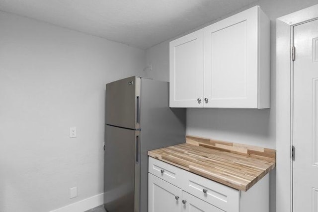 kitchen featuring white cabinets, wood counters, and stainless steel fridge