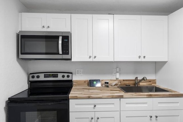 kitchen featuring white cabinets, wood counters, sink, and black / electric stove