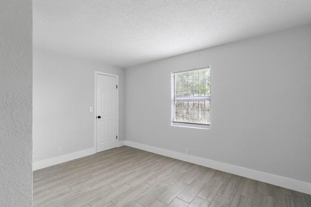 spare room with a textured ceiling and light hardwood / wood-style flooring