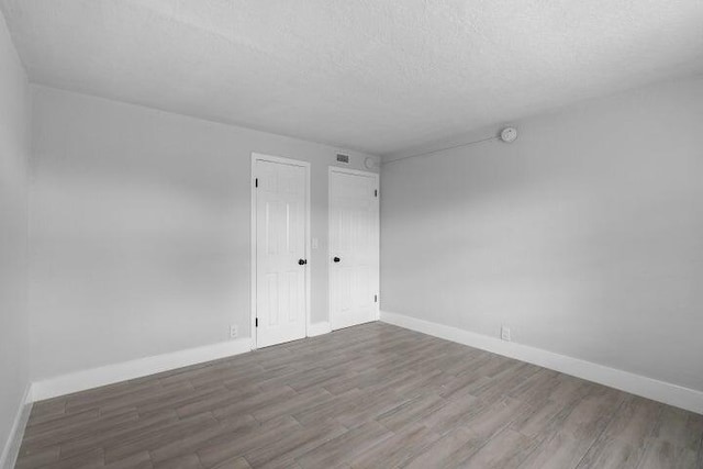 unfurnished room with hardwood / wood-style floors and a textured ceiling