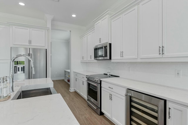 kitchen featuring white cabinets, stainless steel appliances, beverage cooler, and sink