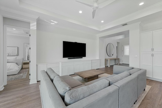 living room with ceiling fan, light hardwood / wood-style floors, and a tray ceiling