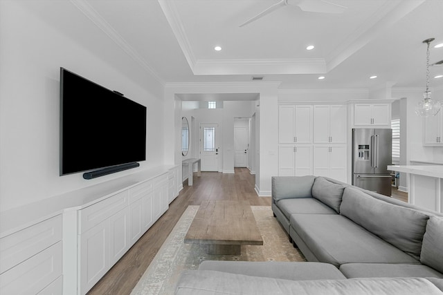 living room with hardwood / wood-style flooring, ceiling fan, a tray ceiling, and crown molding