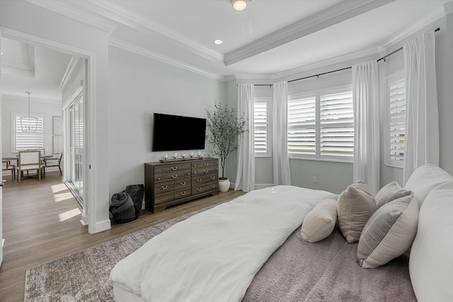 bedroom featuring a raised ceiling, ornamental molding, and hardwood / wood-style floors