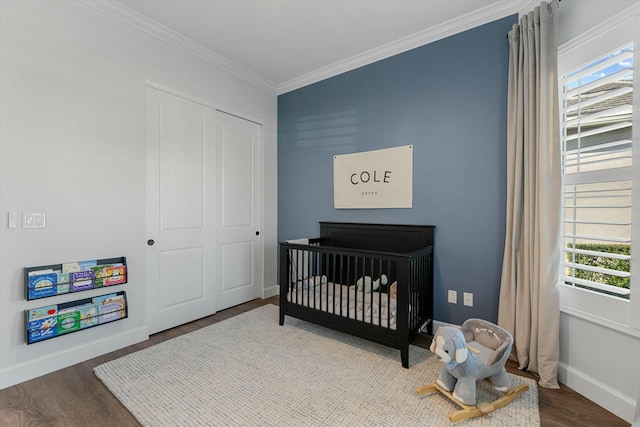 bedroom with a crib, hardwood / wood-style floors, and crown molding