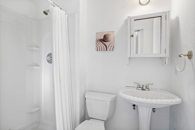 bathroom with curtained shower and toilet