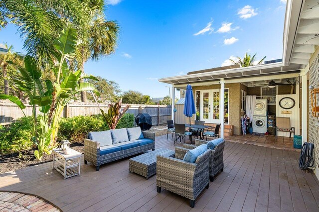 wooden terrace featuring stacked washer / drying machine, ceiling fan, an outdoor hangout area, and grilling area