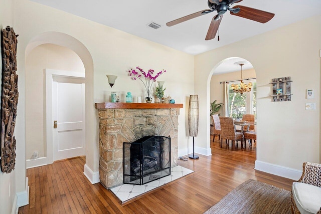 living room featuring a stone fireplace, ceiling fan, and wood-type flooring