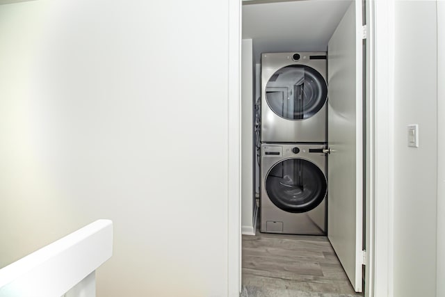 laundry room with stacked washing maching and dryer and light hardwood / wood-style flooring