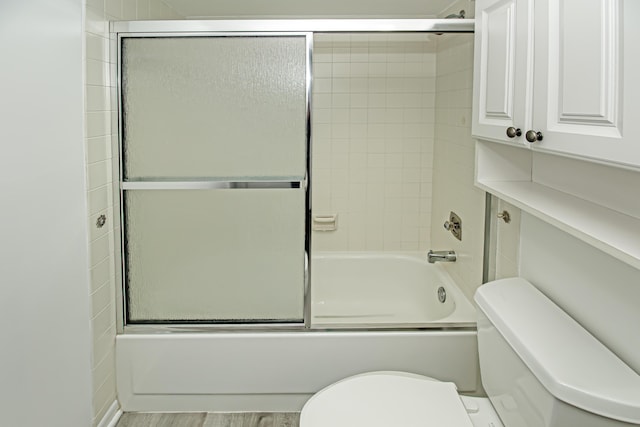 bathroom featuring wood-type flooring, shower / bath combination with glass door, and toilet