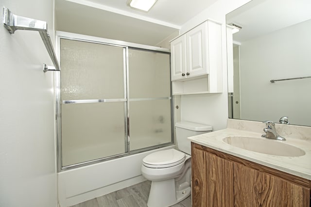 full bathroom with toilet, enclosed tub / shower combo, wood-type flooring, and vanity