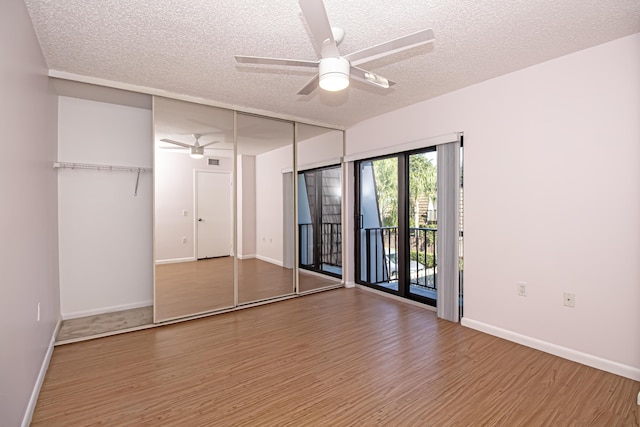 unfurnished bedroom featuring a textured ceiling, a closet, hardwood / wood-style floors, ceiling fan, and access to exterior