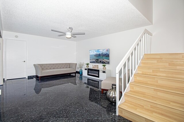 living room featuring a textured ceiling and ceiling fan