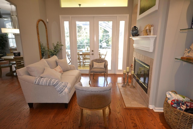 living area featuring a tiled fireplace, french doors, and dark hardwood / wood-style floors