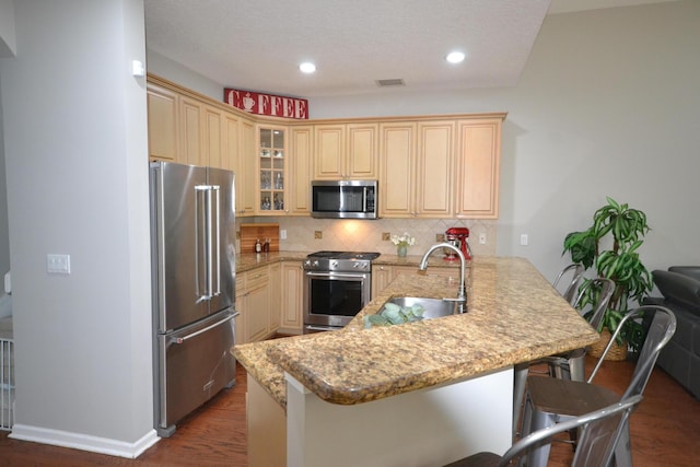 kitchen featuring sink, stainless steel appliances, backsplash, kitchen peninsula, and a breakfast bar area