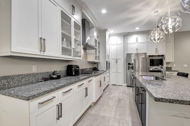 kitchen with hanging light fixtures, white cabinets, wall chimney exhaust hood, and appliances with stainless steel finishes