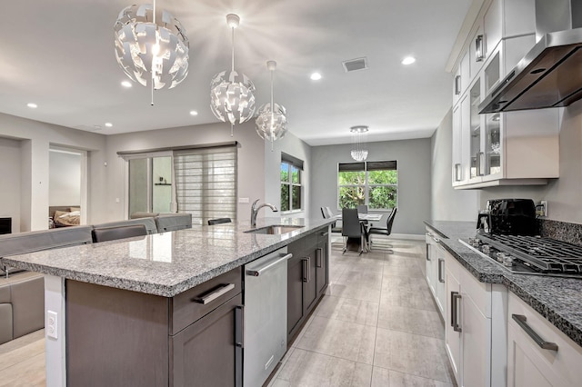 kitchen featuring sink, hanging light fixtures, stainless steel appliances, white cabinets, and wall chimney exhaust hood