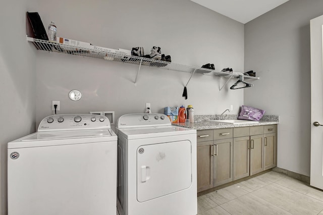 laundry area with cabinets, washing machine and clothes dryer, sink, and light tile patterned floors