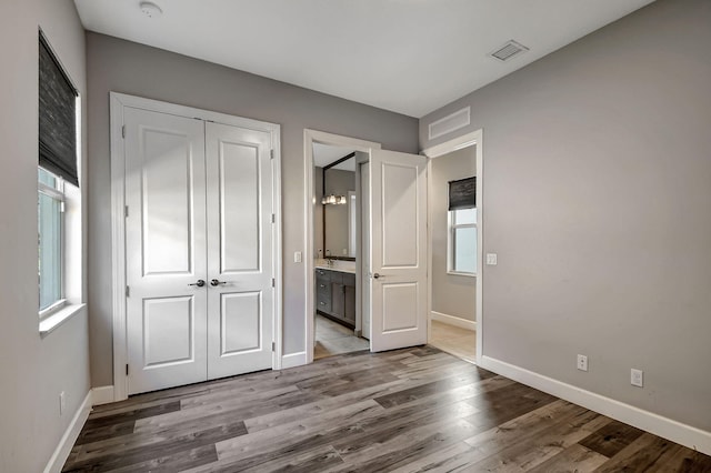 unfurnished bedroom featuring ensuite bath, light hardwood / wood-style flooring, and a closet