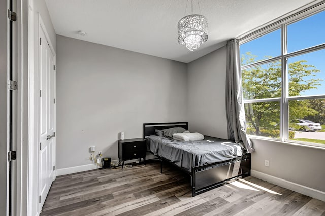 bedroom with hardwood / wood-style floors, a textured ceiling, and an inviting chandelier