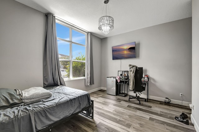 bedroom with hardwood / wood-style flooring, a textured ceiling, and a notable chandelier