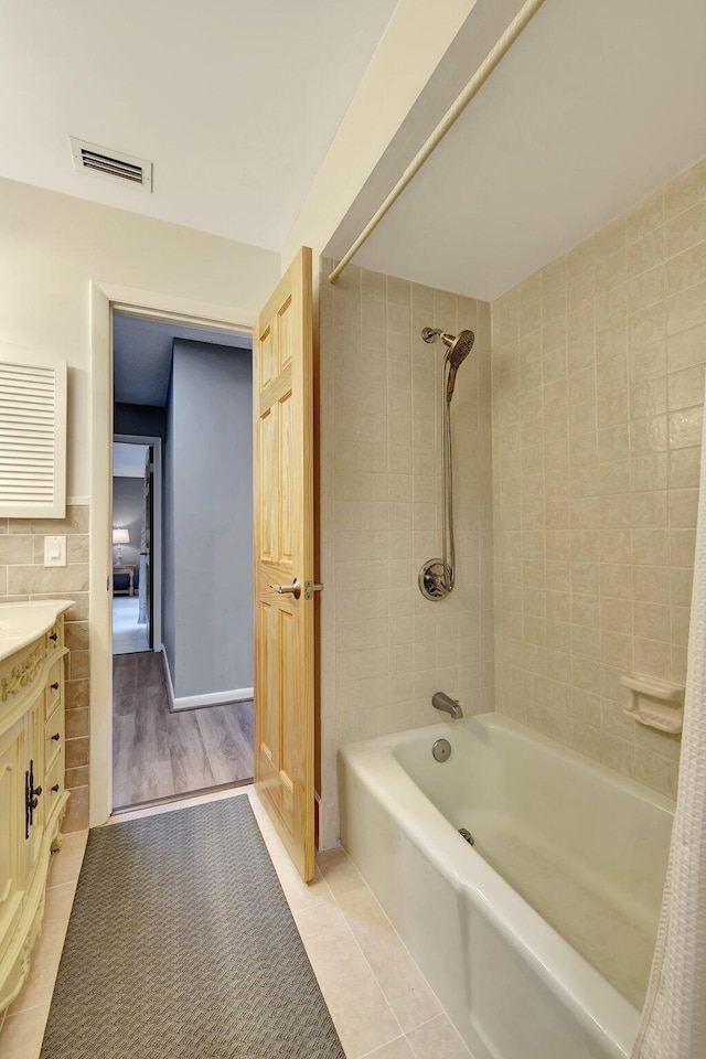 bathroom featuring tile patterned flooring, vanity, shower / bathtub combination with curtain, and tile walls